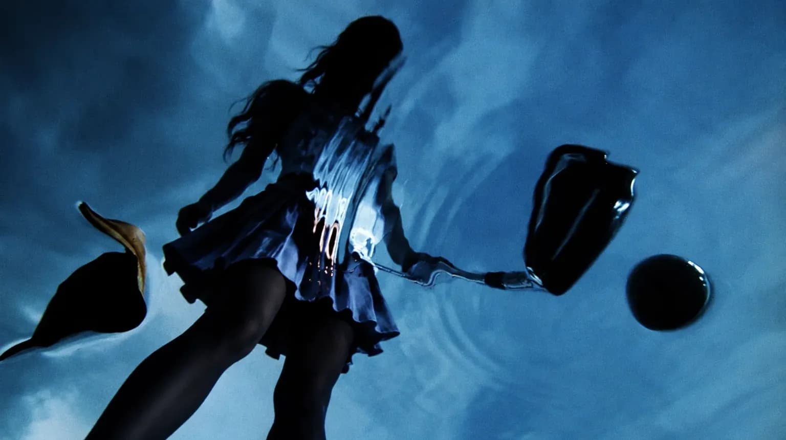 A woman in a skirt seen from below against a dramatic sky.